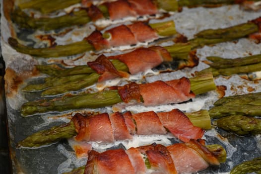 Delicious asparagus wrapped in bacon sizzles on a grill, capturing a warm afternoon's culinary delight outdoors.