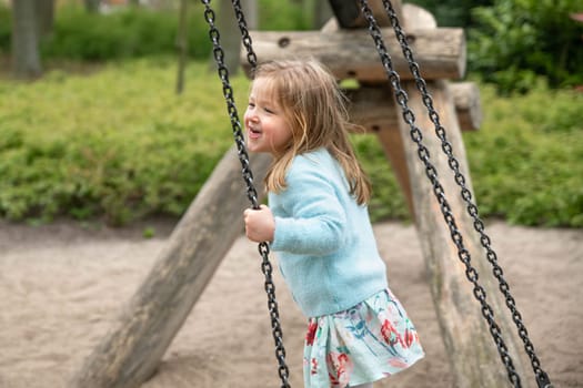 A girl riding on a swing in a park