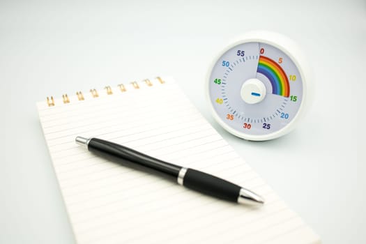 Colorful kids timer with notepad and pen on white background.