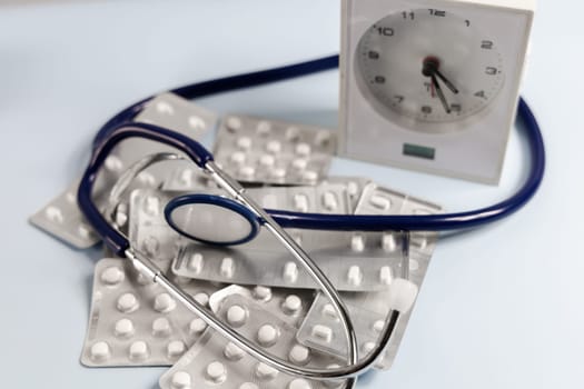 A bunch of pills in blister and a table clock. Concept of taking pills on time. High quality photo