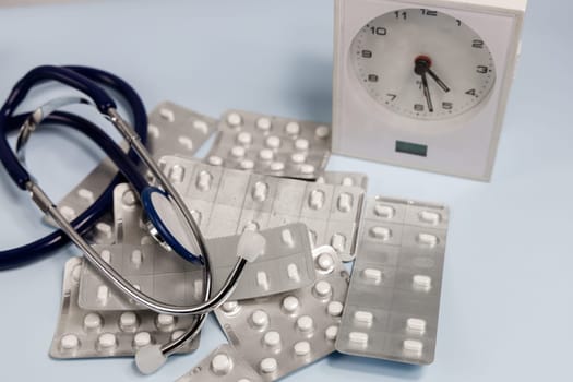 A bunch of pills in blister and a table clock. Concept of taking pills on time. High quality photo