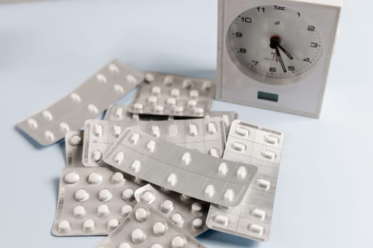 A bunch of pills in blister and a table clock. Concept of taking pills on time. High quality photo