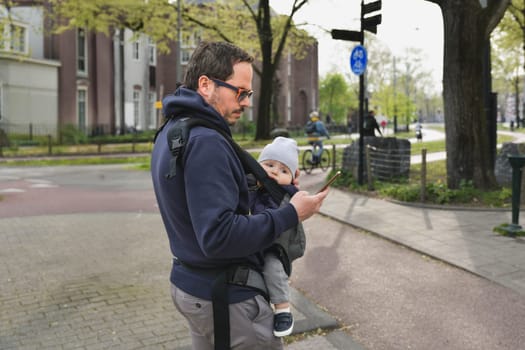 A father carrying his child in a baby sling kangaroo