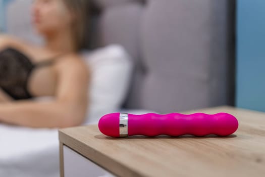 Young woman holding sex toy dildo vibrator in bed.