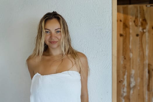 A beautiful woman in a white towel after the sauna. Portrait of a sexy girl after a bath.