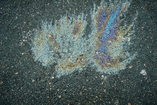 Oil spill creating a unique stain on the asphalt, offering an abstract representation of gasoline and motor oil.