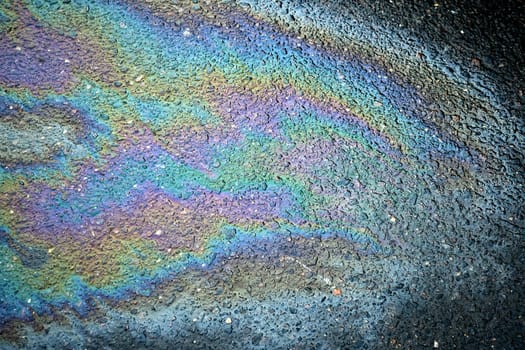 Motor oil stain on the pavement producing an intriguing abstract background of spilled fuel