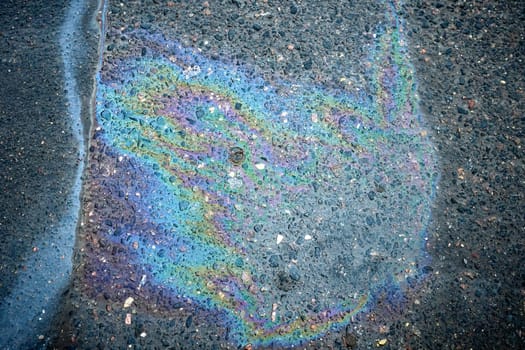 Abstract background of an oil stain on asphalt, resulting from a spill of petrol or motor oil.