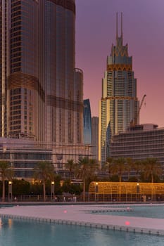 UAE, Dubai, 11 December 2024: The famous shopping center Dubai Mall and Burj Khalifa skyscraper at dusk, Dubai's sights and skyscrapers illuminated at night, palm trees. High quality photo