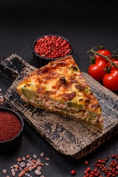 Delicious fresh quiche with broccoli, cheese, spices and herbs cut into pieces on a dark concrete background