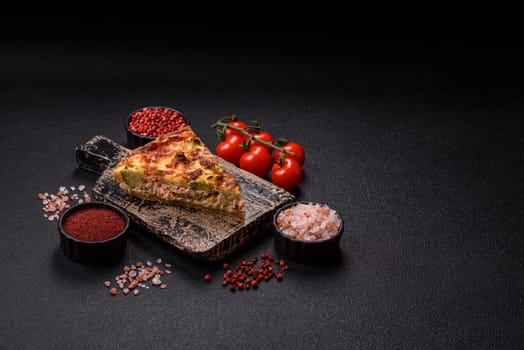 Delicious fresh quiche with broccoli, cheese, spices and herbs cut into pieces on a dark concrete background