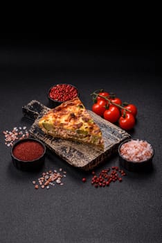 Delicious fresh quiche with broccoli, cheese, spices and herbs cut into pieces on a dark concrete background