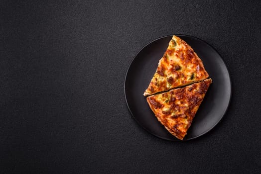 Delicious fresh quiche with broccoli, cheese, spices and herbs cut into pieces on a dark concrete background