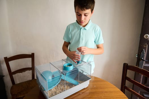 Young boy feeding or taking care of a pet in a cage, displaying affection and responsibility for animals.