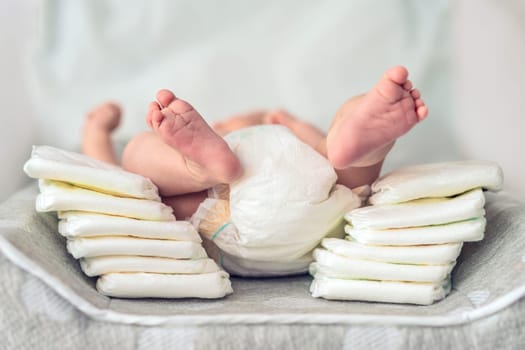 One-month-old baby lying next to a stack of diapers. How to choose the best diapers for your newborn. Baby care, diaper selection, and parenting essentials concept.