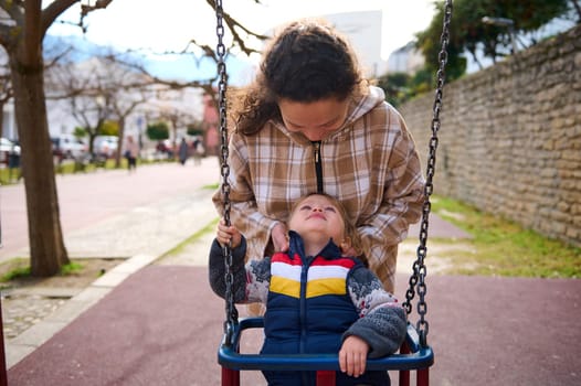A mother lovingly interacts with her child as they enjoy time outdoors at a park playground, emphasizing the bond and joyful connection between parents and children.