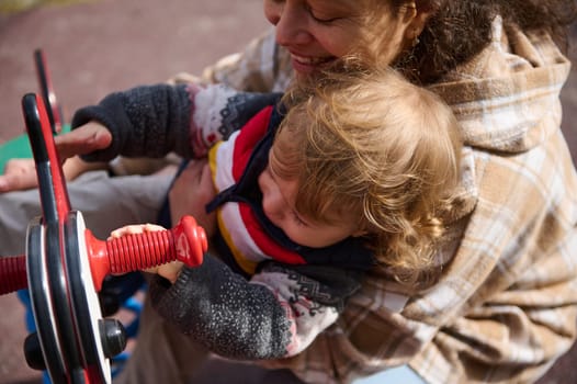 A caregiver lovingly embraces a child while engaging in fun activities at a playground, emphasizing family bonding and joyful moments in nature.