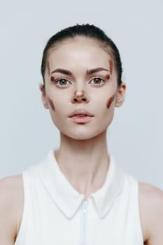 A fashionable young woman features creative face makeup, conveying a bold statement against a minimalist backdrop, merging art and beauty for a fresh seasonal look.