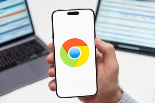 PRAGUE, CZECH REPUBLIC - JANUARY 21 2024: Chrome logo on the screen of smartphone in mans hand on the workplace background.