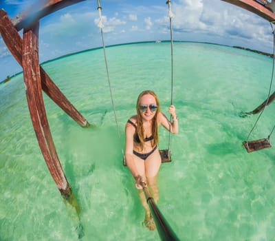 Woman standing in the crystal-clear waters of Lake Bacalar, Mexico, enjoying the serene beauty of the landscape. Tranquil moment in nature, outdoor escape, and relaxation concept.