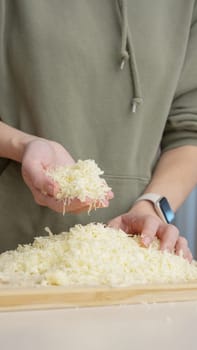 Grated cheese falls out of the cook's hand. Grated cheese for pizza