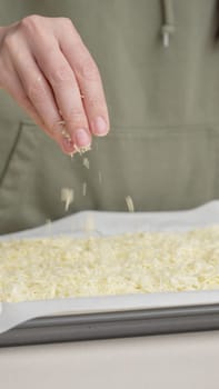Grated cheese falls out of the cook's hand on pizza. Homemade pizza. Grated cheese for pizza