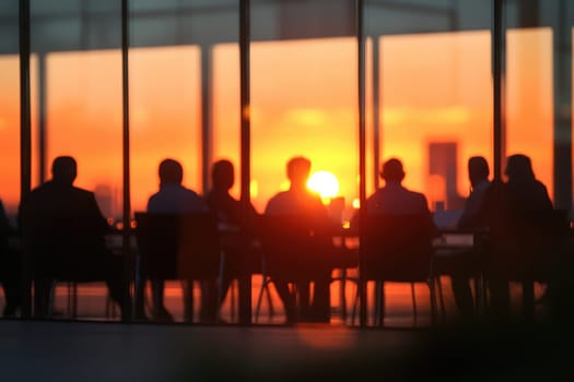 A defocused view captures a group of executives engaged in a meeting, framed by a stunning sunset. The warm glow enhances the corporate atmosphere and teamwork.