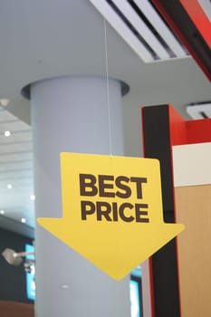 Bright sign hanging from the ceiling showing best price in a mall.