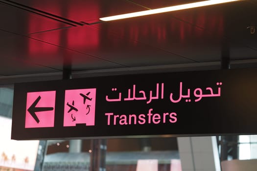 Directional sign for transfers at a busy international airport terminal.