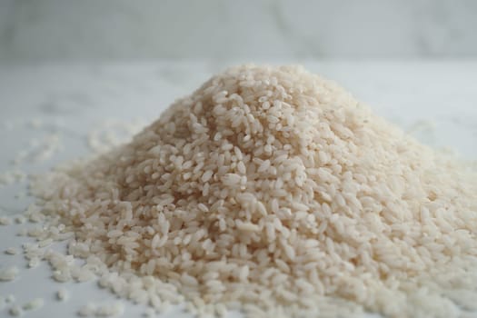 A small mound of uncooked white rice sits on a light surface.
