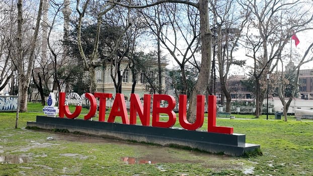 Colorful sign stating Istanbul contrasts with bare trees nearby.