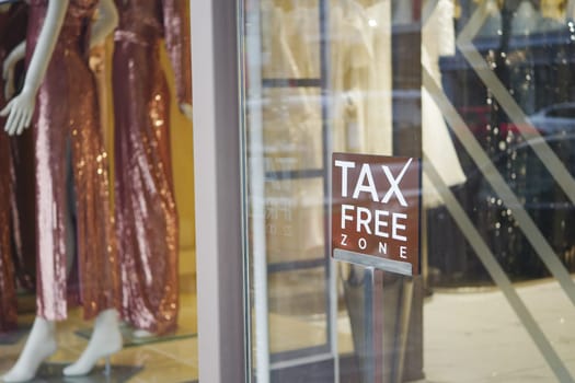 Storefront showcases elegant dresses and tax free sign.