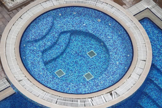 Relaxation area featuring a circular hot tub and blue mosaic tiles.