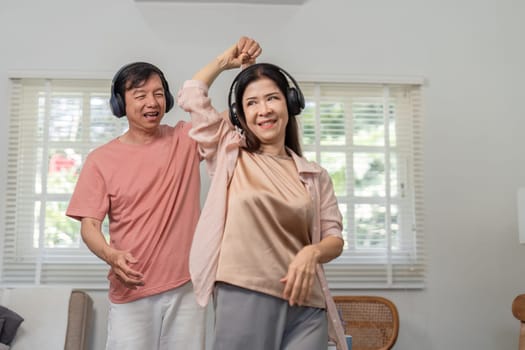 An older couple shares a joyful dance together, wearing headphones and enjoying the music in their bright and inviting home.