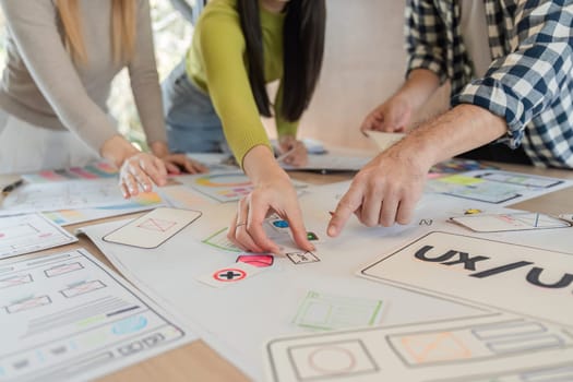 A diverse group of team members analyzing UXUI design prototypes and providing feedback during a collaborative brainstorming session at a modern office table.