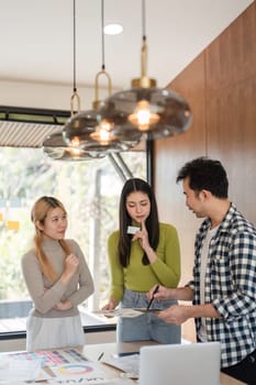 A diverse team discussing design ideas and reviewing materials in a bright, modern office space.