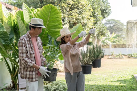 A diverse couple happily showcasing their potted herbs while gardening in a sunny backyard, enjoying a productive day surrounded by greenery.