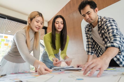 A diverse group of professionals engaged in a discussion about design ideas while collaborating around a table in a modern office environment.