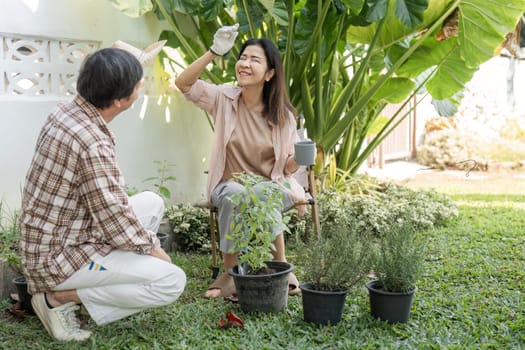 A diverse couple joyfully gardening in their sunny backyard, sharing cheerful moments while engaging with potted plants and enjoying each other's company.
