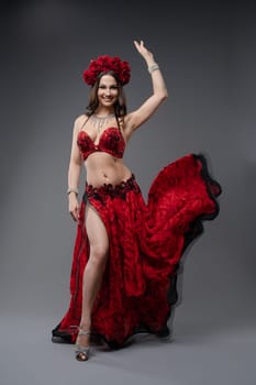 A skilled dancer showcases graceful movements in a stunning red costume complete with flowers, capturing the audience's attention.