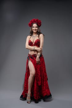 A dancer showcases a vibrant red costume adorned with floral accents while striking a confident pose, capturing the essence of performance art.