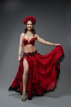 A talented belly dancer showcases her skills in a stunning red ensemble featuring floral accents. The performance exudes elegance and energy.