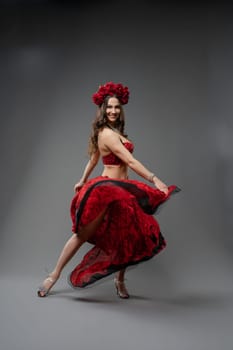 A dancer showcases her skills in a stunning red dress, spinning elegantly under studio lights. Her floral headpiece adds to the festive ambiance.