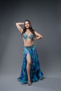 Dancer displays a colorful costume while posing gracefully against a neutral backdrop. The performance highlights her skill and artistry.