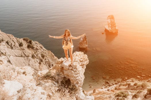 Woman travel sea. Happy tourist taking picture outdoors for memories. Woman traveler looks at the edge of the cliff on the sea bay of mountains, sharing travel adventure journey.