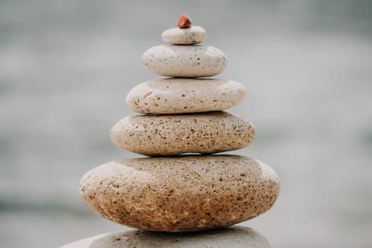 Pyramid stones on the seashore with warm sunset on the sea background. Happy holidays. Pebble beach, calm sea, travel destination. Concept of happy vacation on the sea, meditation, spa, calmness.