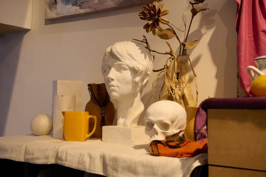 Close-up. Plaster skeleton and objects for drawing, a head model on the desk, displayed on a table in creative art studio. Art class. Workshop. Painting and drawing. Fine art concept. Still life