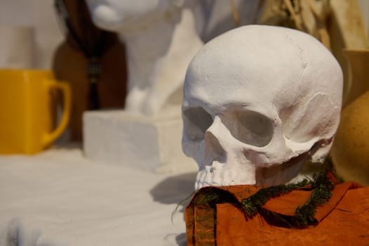 Close-up photography. Plaster figurine of human skeleton, head on the desk in art studio or painter workshop, for education and learning drawing. Copy advertising space. Artist's workplace. Still life