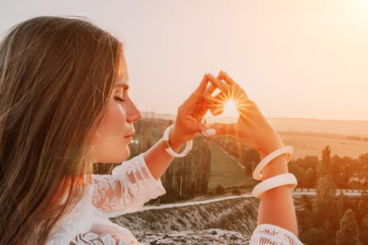 Romantic beautiful bride in white dress posing with sea and mountains in background. Stylish bride standing back on beautiful landscape of sea and mountains on sunset