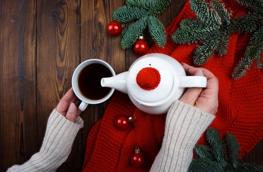 Women's hands pour tea from a teapot into a cup. High quality photo